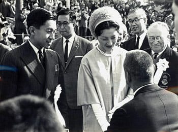 Close up of Crown Prince Akihito and Empress Michiko meeting representatives of teams during the Opening Ceremony of the 1964 Tokyo Paralympic Games. Paralympic founder Ludwig Guttmann is in the background. / Wikipedia